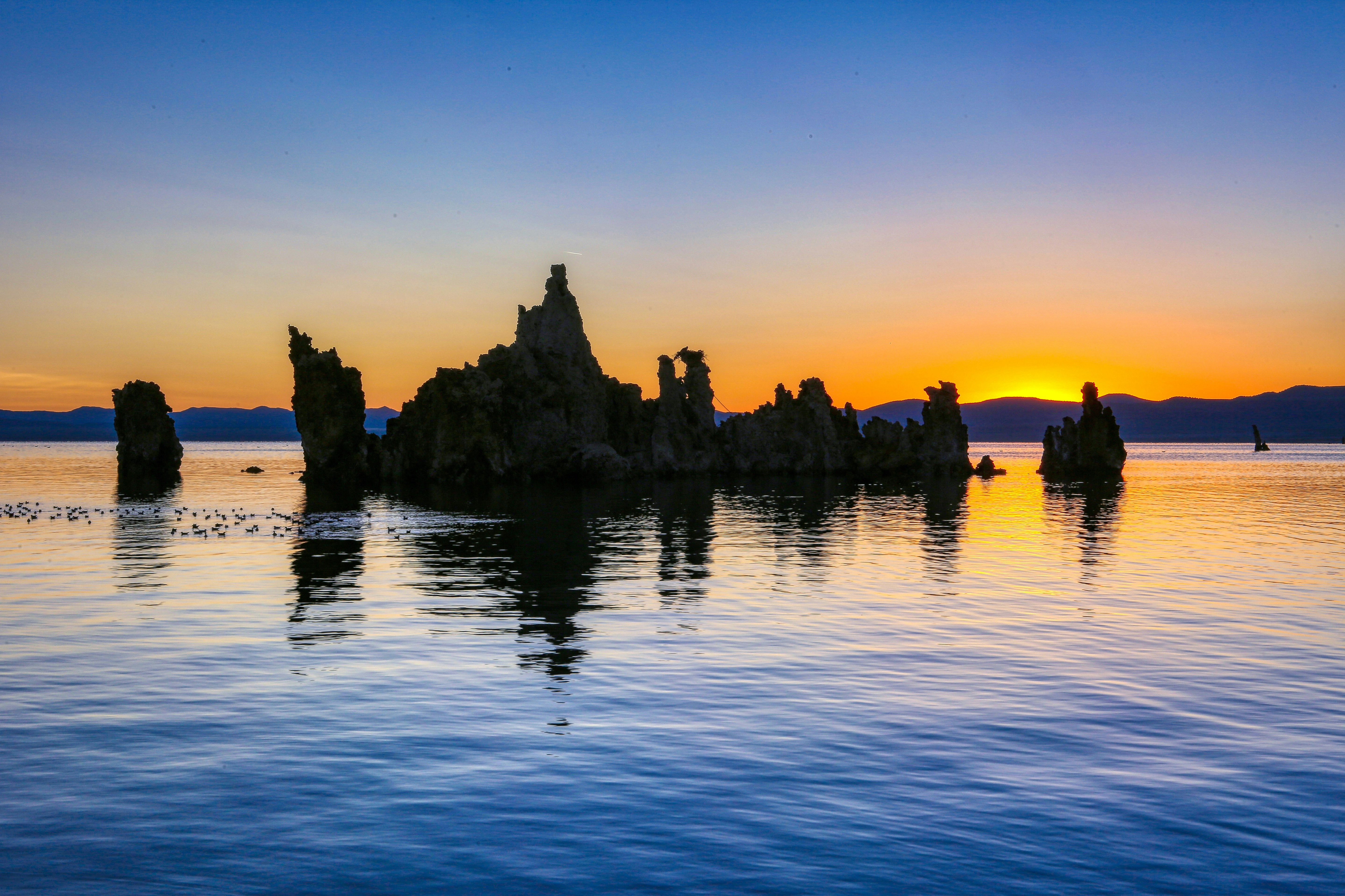 silhouette of mountain near body of water during sunset